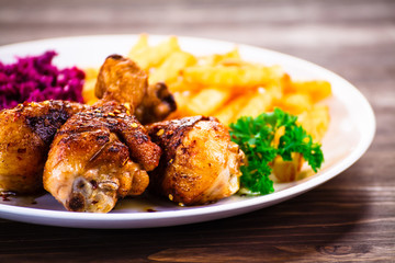 Roast chicken drumsticks with chips and vegetables