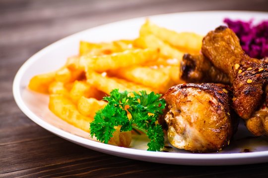 Roast chicken drumsticks with chips and vegetables