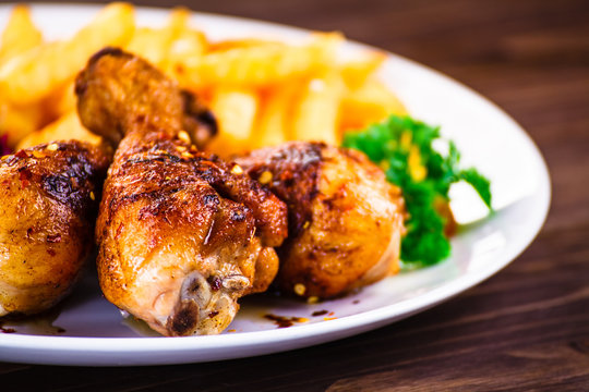 Roast chicken drumsticks with chips and vegetables