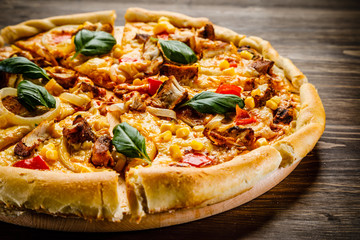 Pizza with chicken and vegetables on wooden background
