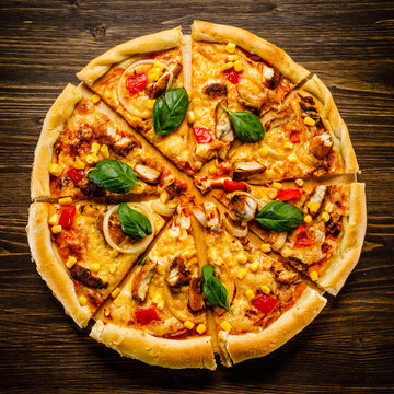 Pizza with chicken and vegetables on wooden background