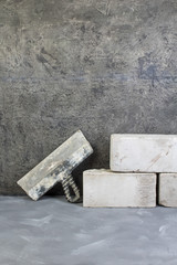 bricks, putty knife on the gray concrete background. Copy space. Top view.