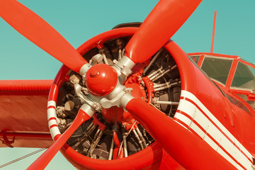 Red biplane on sky background. Close-up with engine and propeller