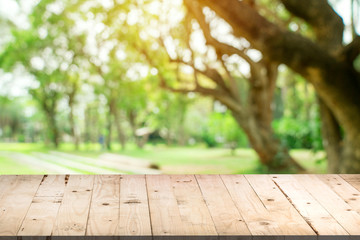 Empty wood table and defocused bokeh and blur background of garden trees in sunlight, display...