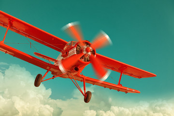 Red biplane flying in the cloudy sky. Retro style - obrazy, fototapety, plakaty
