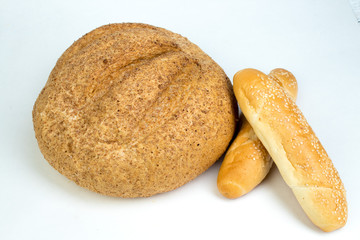 Many mixed breads and rolls of baked bread, on wooden table background.