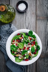 Green salad spinach bowl with quinoa, pomegranate, walnuts, goat cheese and dried cranberries.
