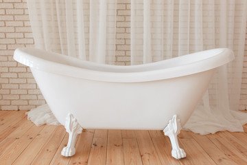 Bathroom with white brick wall and a tub standing on a wooden decoration element