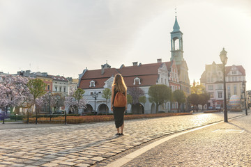 Woman in a grey dress and orange bag is walking on the street in Kluczbork, Poland