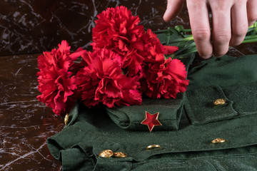 hand put the red flowers on the military uniform