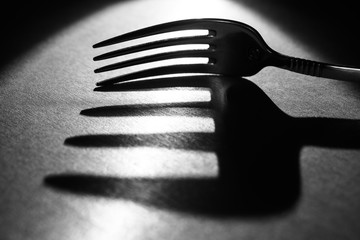 fork on the table in a beam of light with a large shadow