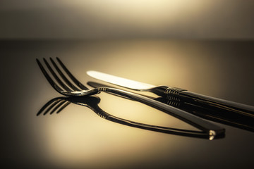 fork and knife on the table in a beam of light