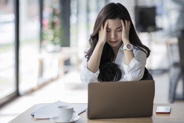 Stressed female designer sitting at desk in modern office