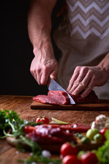 Strong professional man's hands cutting raw beefsteak, selective focus, close-up