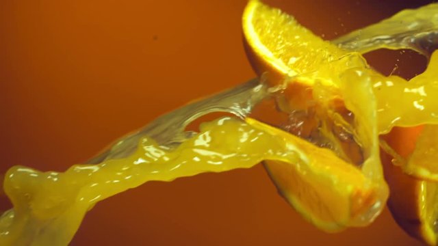 Orange slices falling into stream of orange juice