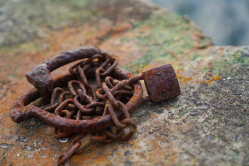 A rusty padlock with a chain for boats near the sea