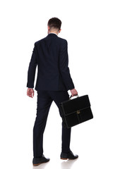 back view of businessman with suitcase walking