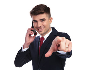 smiling businessman talking on the phone is pointing finger