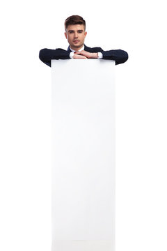 handsome businessman resting elbows on a big white empty board