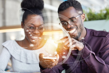 Photo of happy African American delighted female and male look happily into screen of smart phone, touch screen as recieve message. Double exposure and visual effects. Modern technologies concept