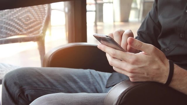 Man's hands texting on silver metallic mobile device.  Cell phone usage and connectivity for 5G and 4G networks.