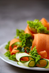 Artistically served vegetable salad with carrot, cucumber, letucce over white background, selective focus
