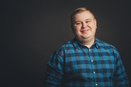 Portrait of smiling fat man on black background