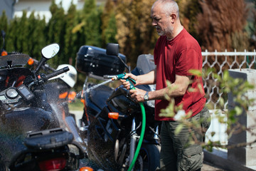 Naklejka premium Adult and experienced biker cleaning and washing his motorcycle