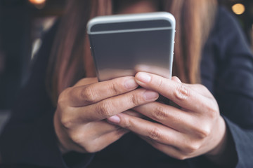 Closeup image of a woman holding , using and looking at smart phone