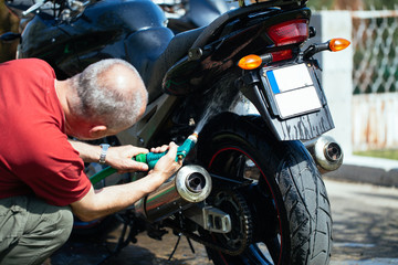 Fototapeta na wymiar Adult and experienced biker cleaning and washing his motorcycle