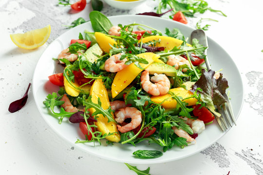 Fresh Avocado, Shrimps, Mango salad with lettuce green mix, cherry tomatoes, herbs and olive oil, lemon dressing. healthy food