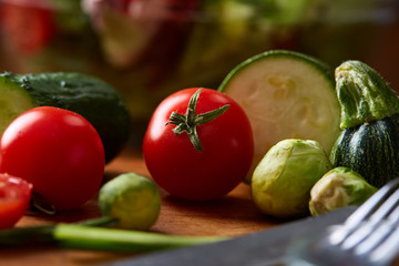 Fresh vegetable salad and ripe veggies on cutting board over wooden background, close up, selective focus