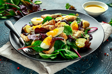Warm Smoked Mackerel Salad with new potato, eggs, green lettuce mix in a plate.