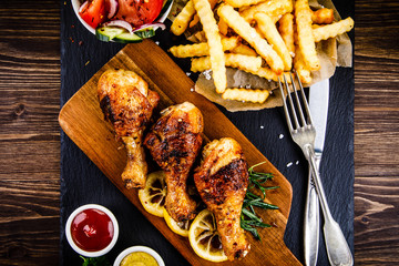Grilled chicken drumsticks with French fries and vegetables