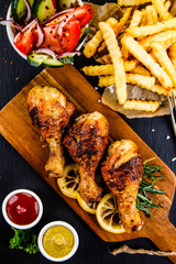 Grilled chicken drumsticks with French fries and vegetables
