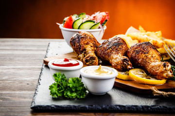 Grilled chicken drumsticks with French fries and vegetables
