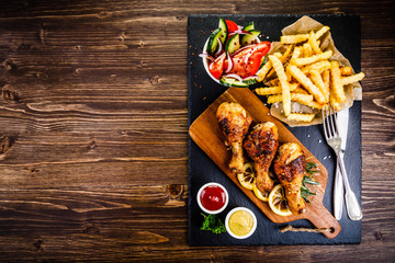 Grilled chicken drumsticks with French fries and vegetables