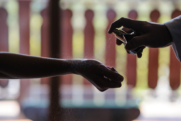 applying perfume on beautiful young woman wrist