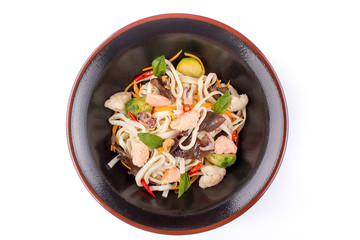 Wheat noodles with seafood and vegetables under teriyaki sauce, isolated on white background. Wheat noodles in a black plate.