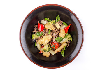 Buckwheat noodles with chicken and pineapple under teriyaki sauce, isolated on white background. Buckwheat noodles in a black plate.