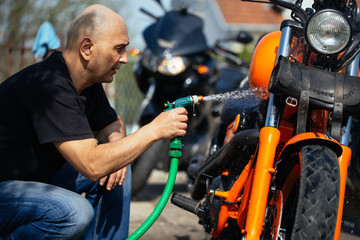 Adult and experienced biker cleaning and washing his motorcycle