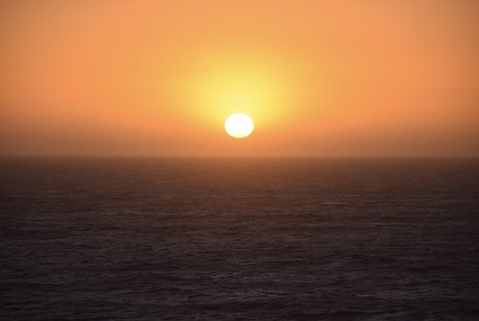 Bright orange sunset lowering peacefully over the ocean © ChrisMills