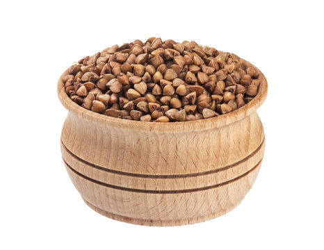Isolated buckwheat seeds. Wooden bowl with buckwheat groats on white background. Close-up