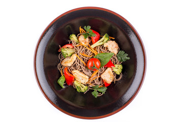 Buckwheat noodles with chicken and vegetables under teriyaki sauce, isolated on white background. Buckwheat noodles in a black plate.