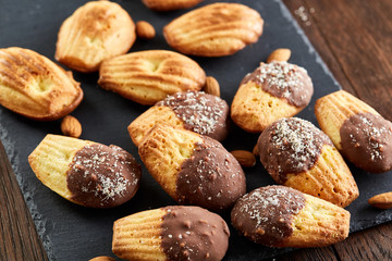 Freshly baked almond cookies with almond on stone board over wooden background, top view, selective focus.