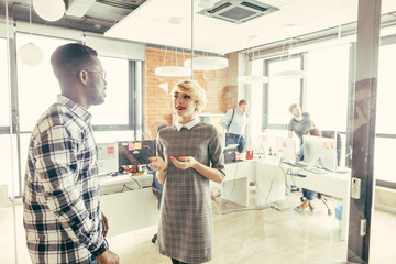 Sales blonde manage and black partner standing and having a dialogue at work. chip the ivories