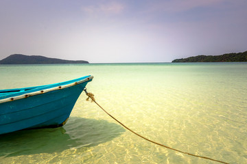 Obraz premium A blue boat with a rope against calm, turquoise and crystal clear water.