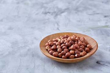 Hazelnuts in ceramic bowl on wihite background with copy space, top view, selective focus.