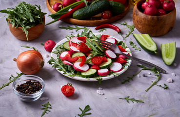 Fresh red radish in wooden bowl among plates with vegetables, herbs and spicies, top view, selective focus.