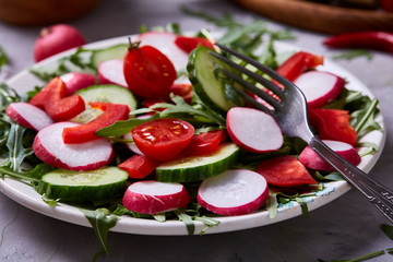 Fresh red radish in wooden bowl among plates with vegetables, herbs and spicies, top view, selective focus.